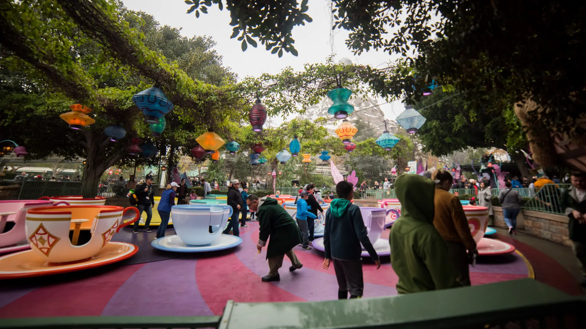 Real photo of Mad Tea Party teacups at Disneyland Fantasyland, colorful cups on the spinning platform with hanging lanterns and the Matterhorn behind