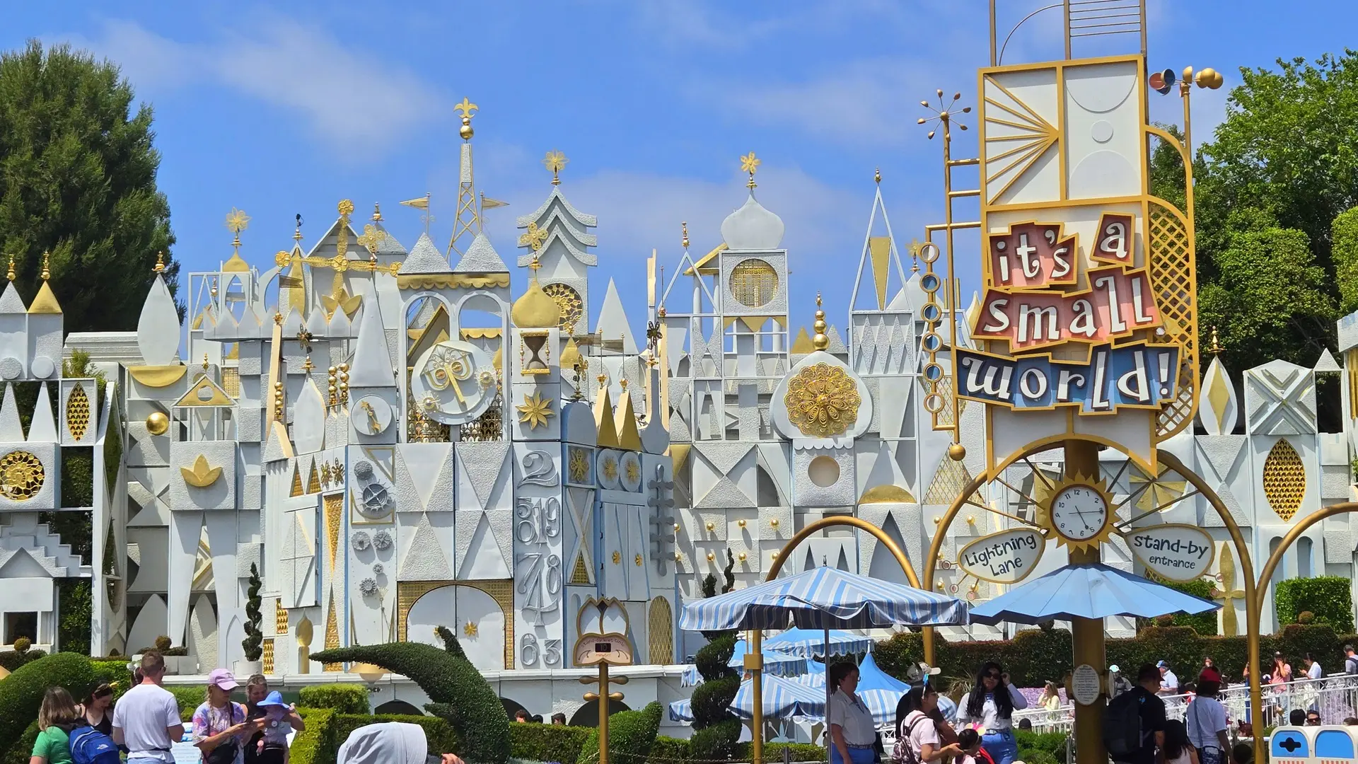 Daytime view of the white and gold it's a small world facade and entrance sign at Disneyland Park